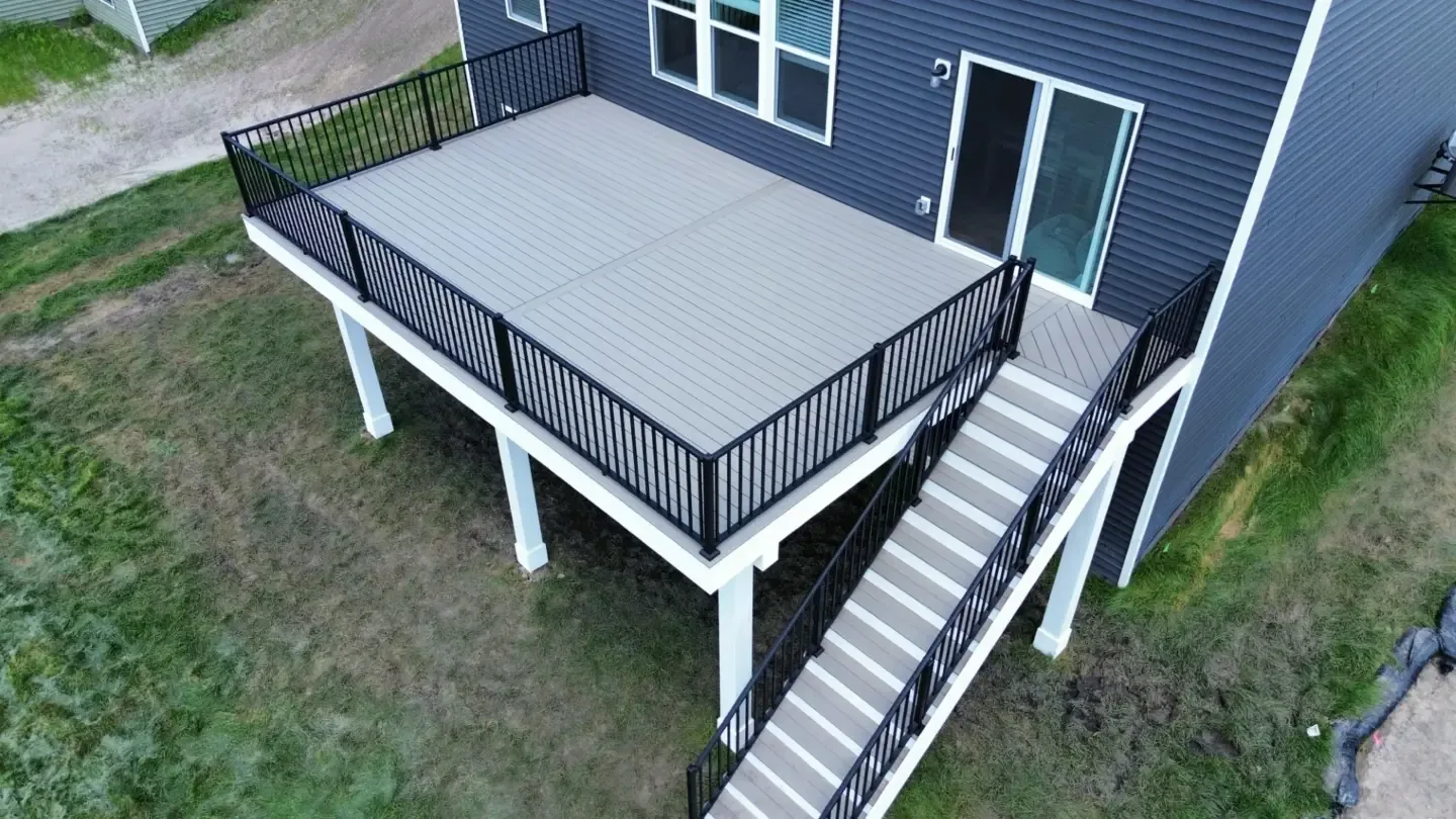 Elevated composite deck with black metal railing and a wide staircase leading to the yard
