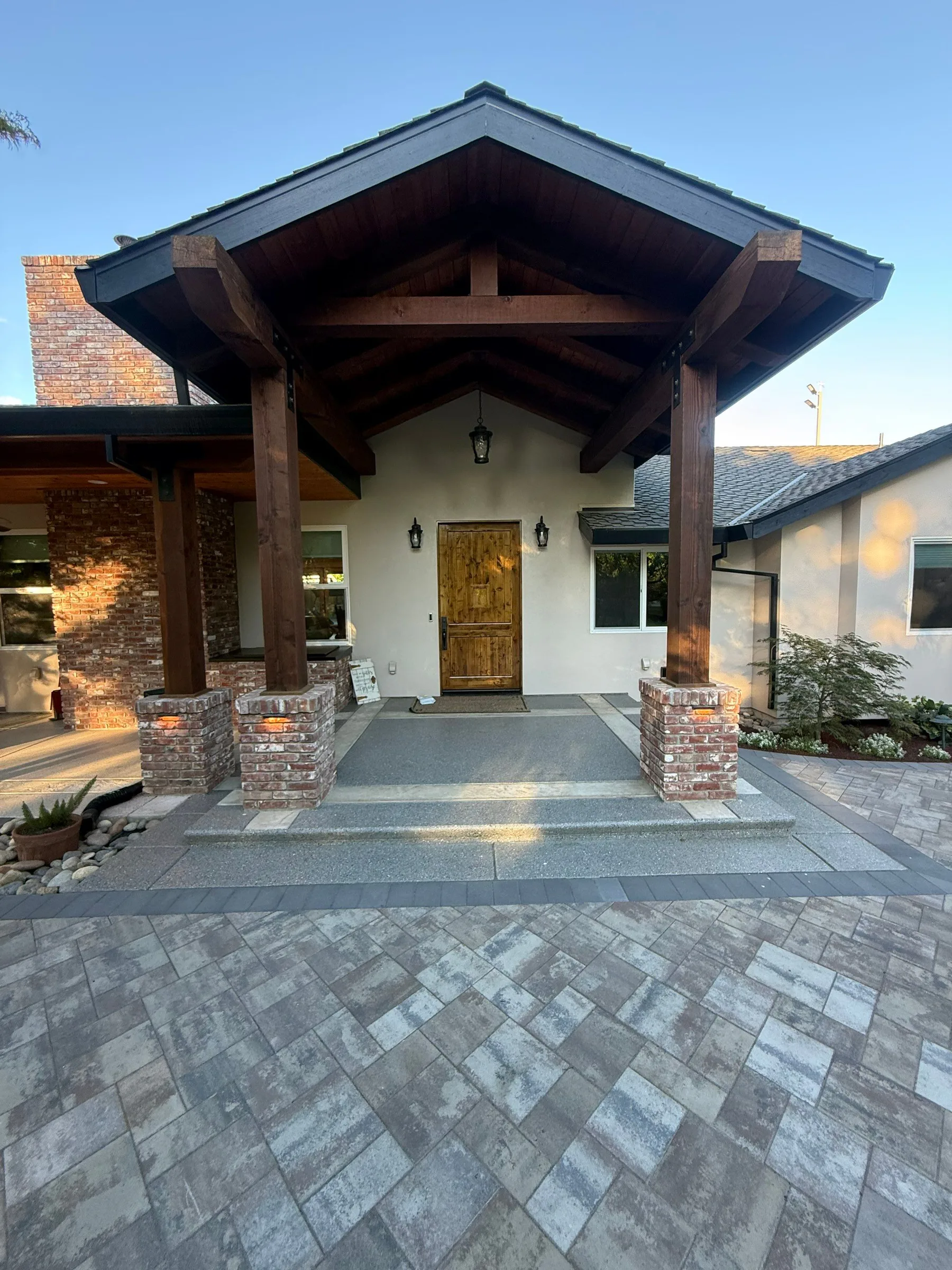 Paver patio and walkway beneath a covered home entry