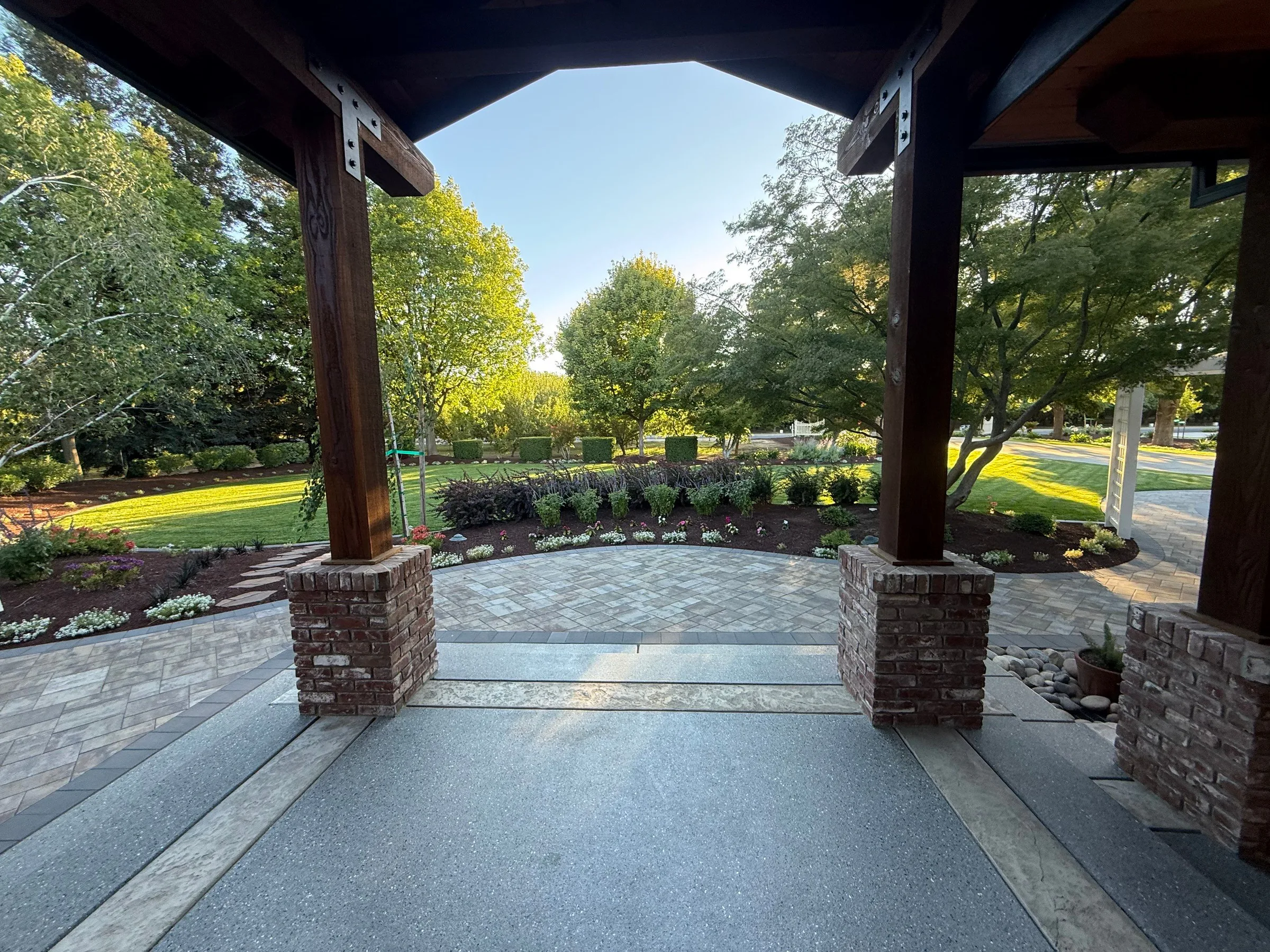 Covered paver patio opening to a finished Haven Outdoors landscape