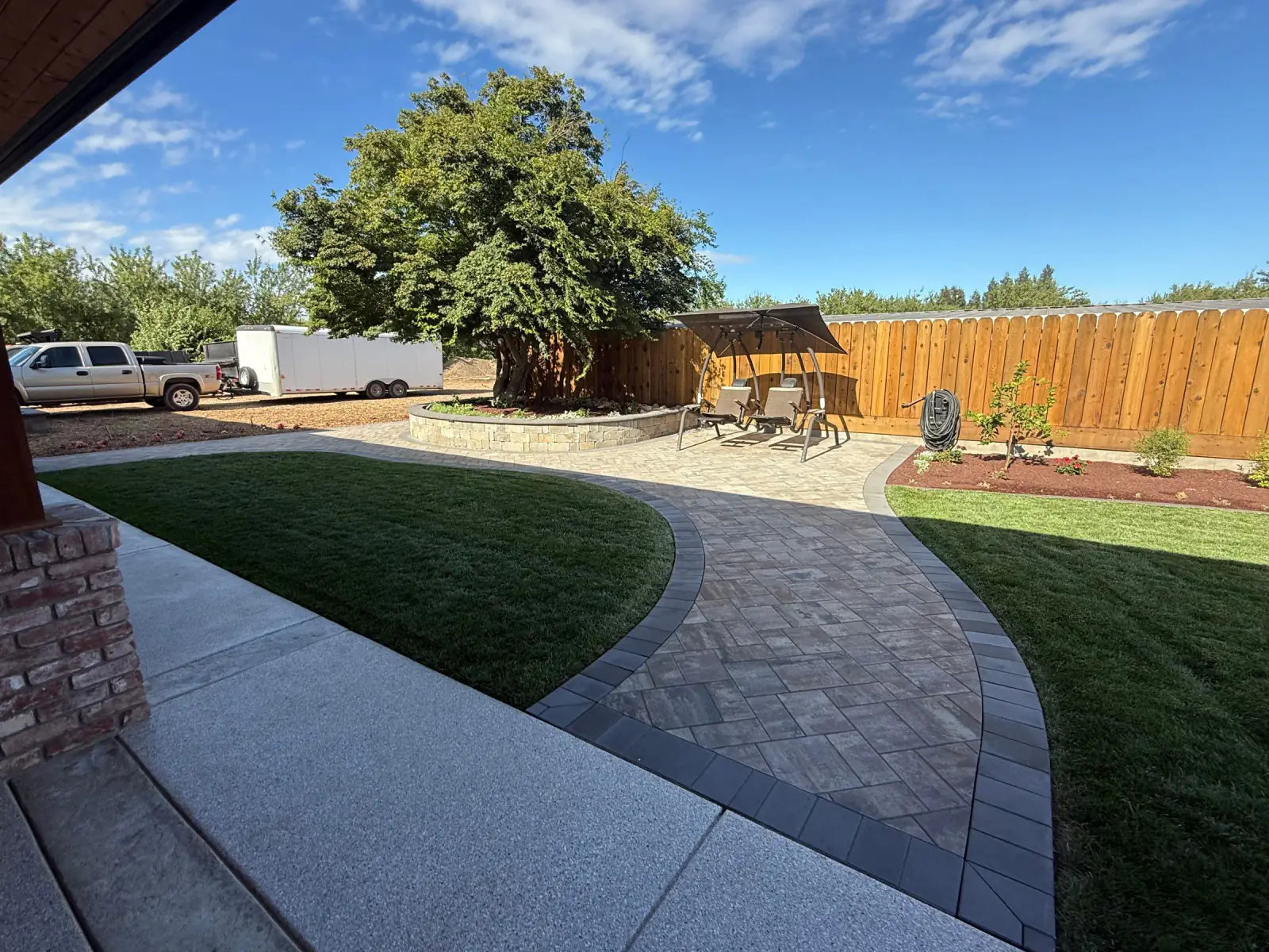 Curved paver path crossing a finished lawn toward a pergola