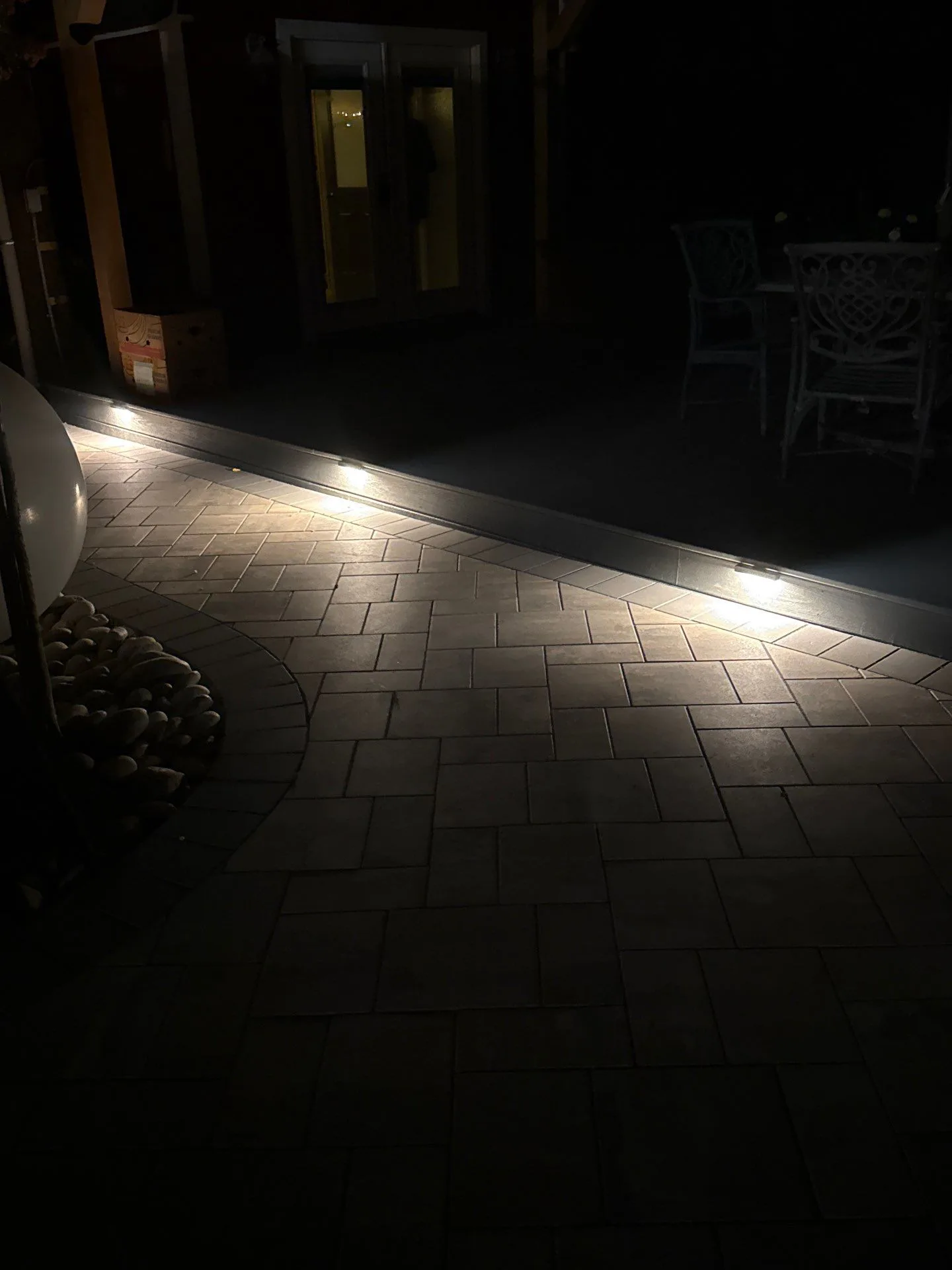 Landscape lighting along a Haven Outdoors paver patio at night