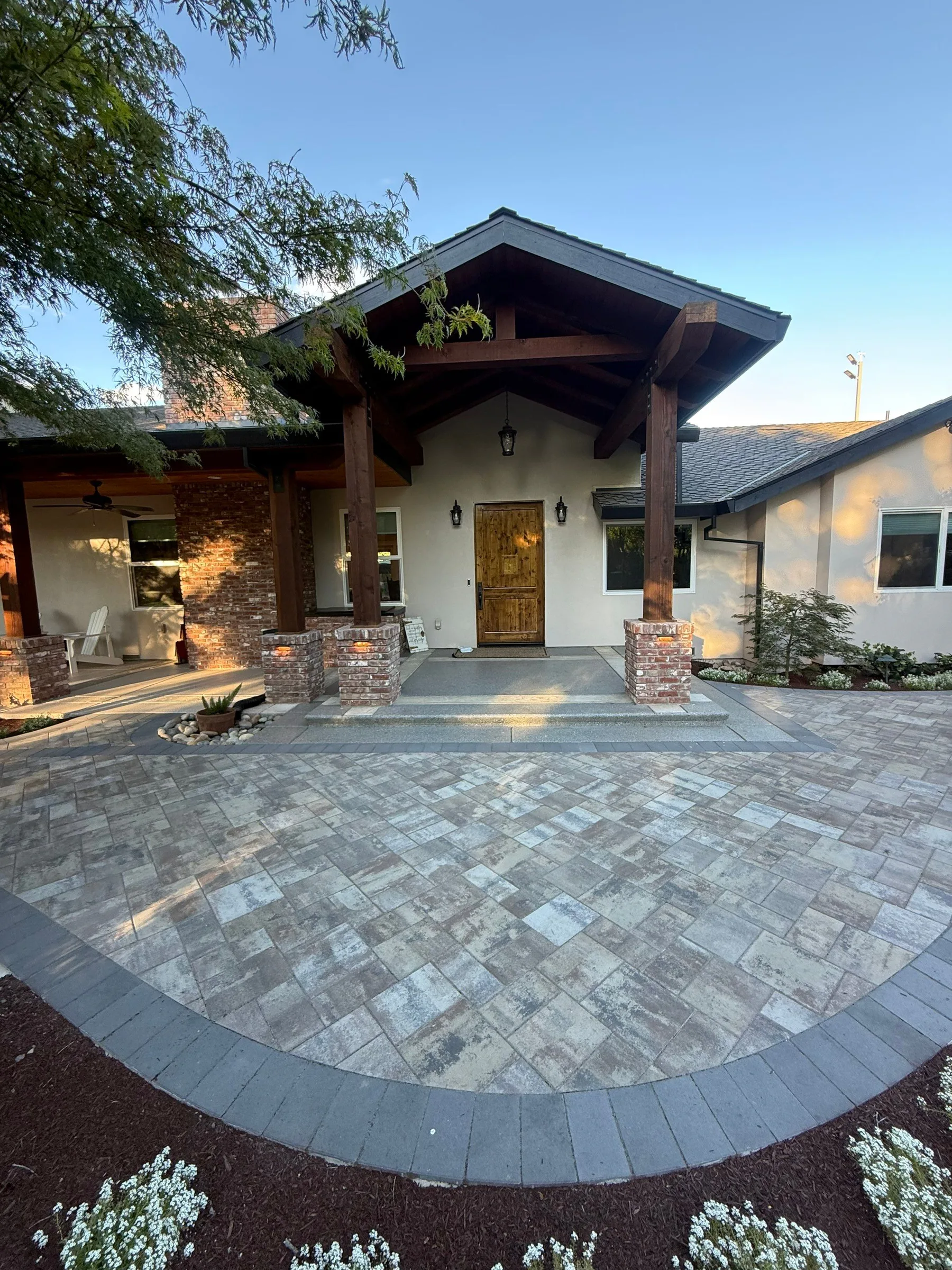 Covered outdoor area with a paver patio beside landscaped planting beds