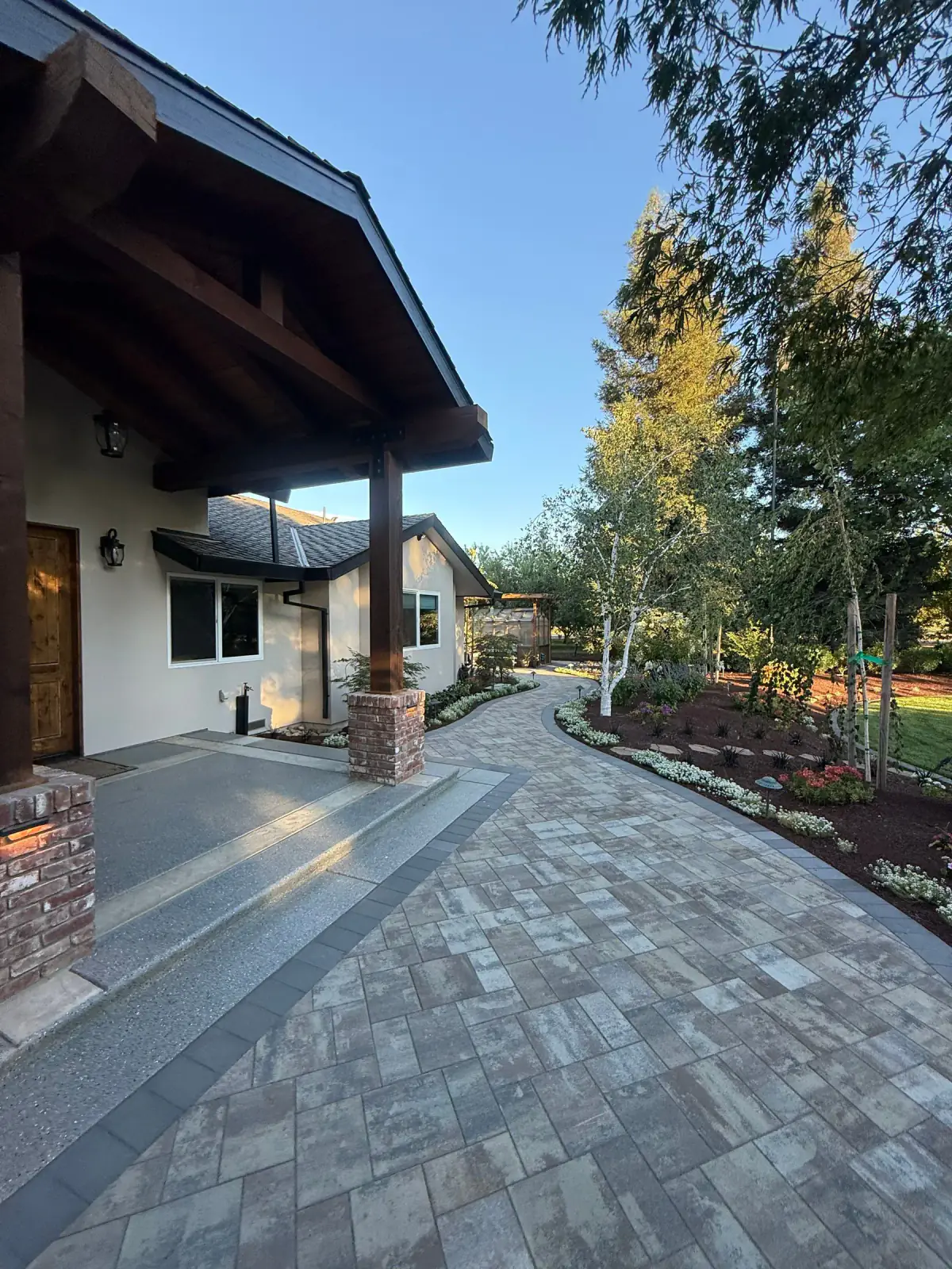 Paver walkway leading from a covered home entry through landscaped planting beds