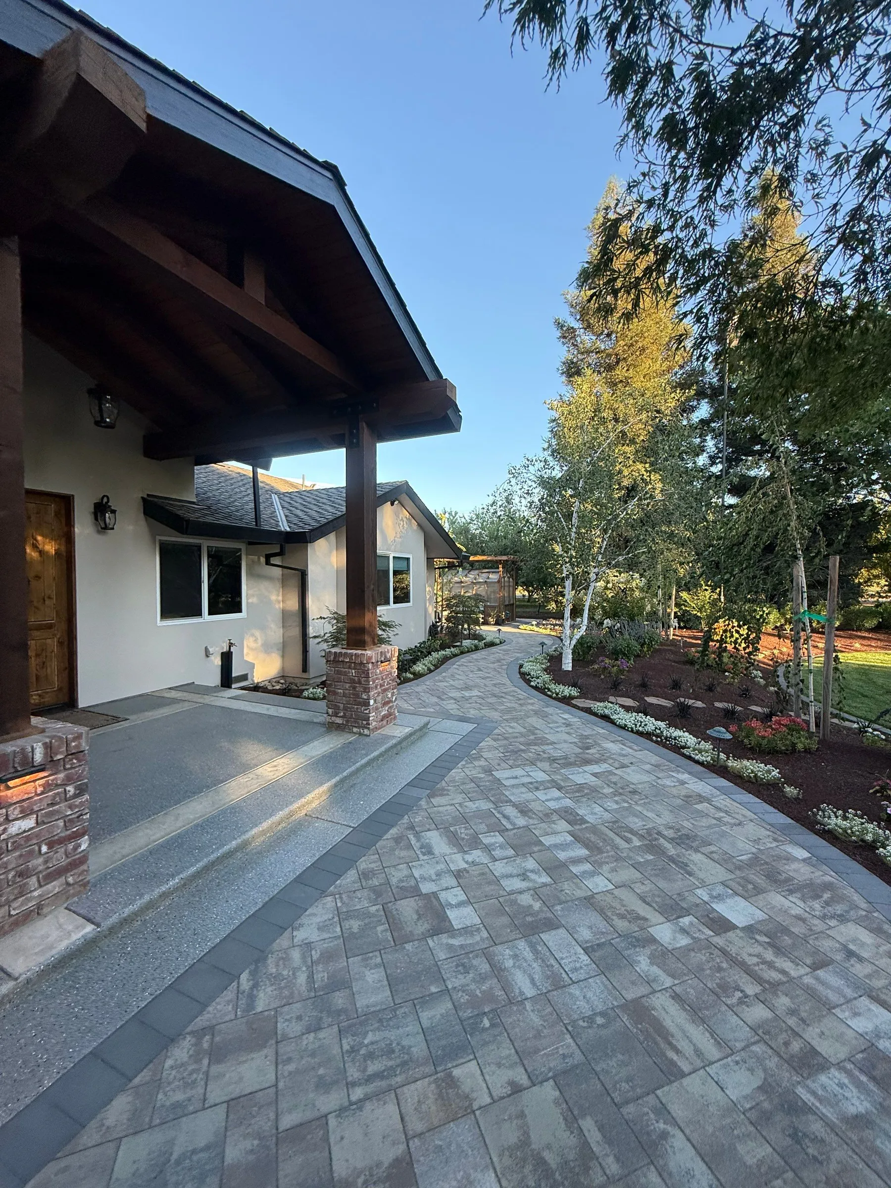 Paver walkway leading from a covered home entry through landscaped planting beds