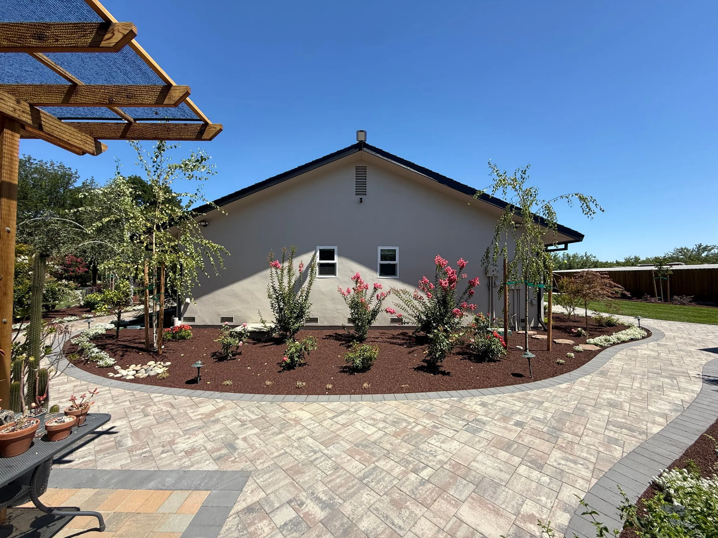 Side-yard paver patio beside a mulched planting bed