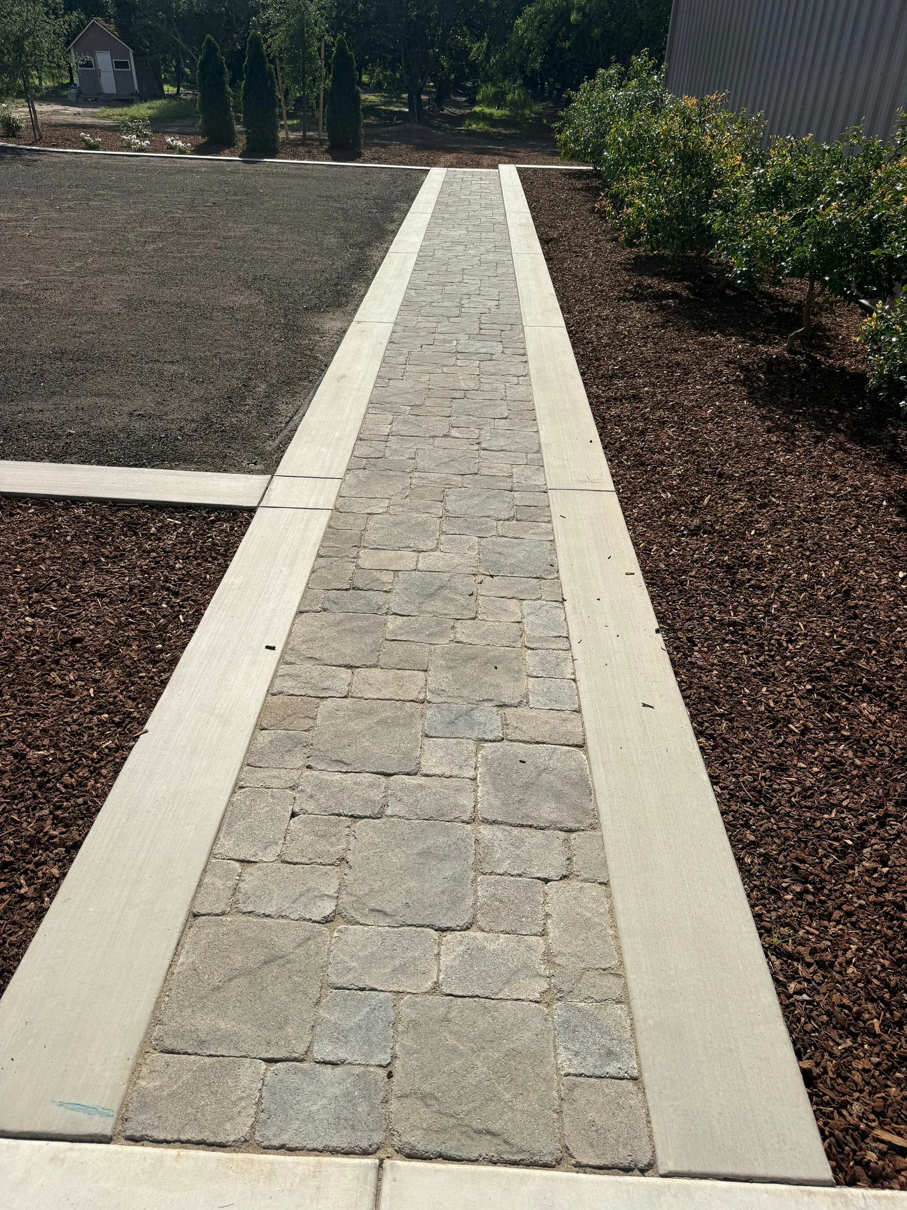 Two-tone paver walkway with a dark border beside a landscaped lawn