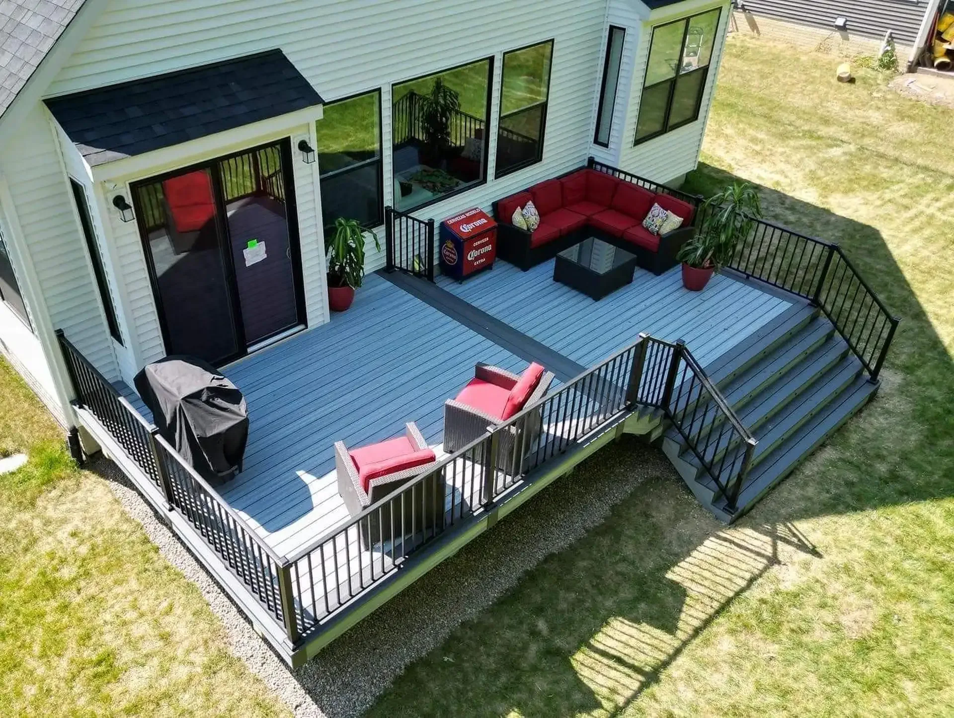 Multi-level backyard deck with black railing, broad stairs, and connections to the lawn