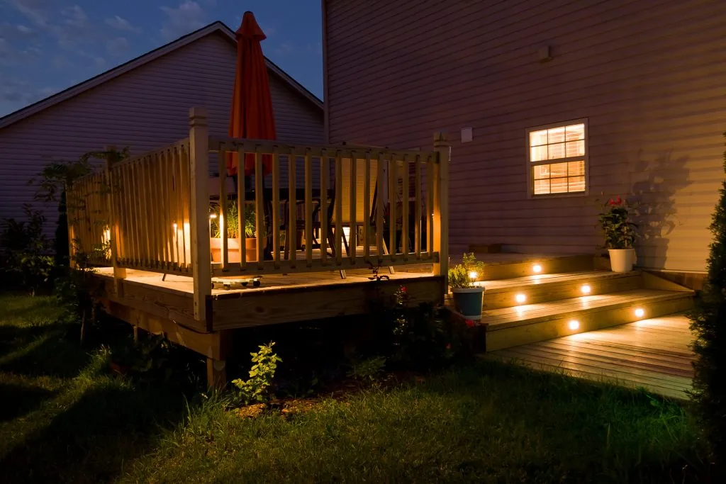 Wood deck and wide steps illuminated by integrated lighting at dusk